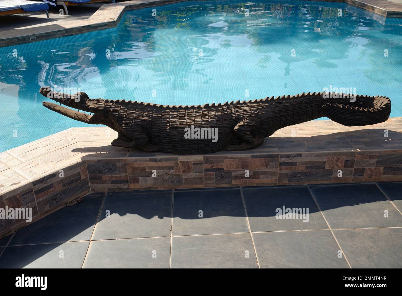 Eine hölzerne Skulptur eines Krokodils neben einem Swimmingpool in Gambia, Westafrika. Stockfoto