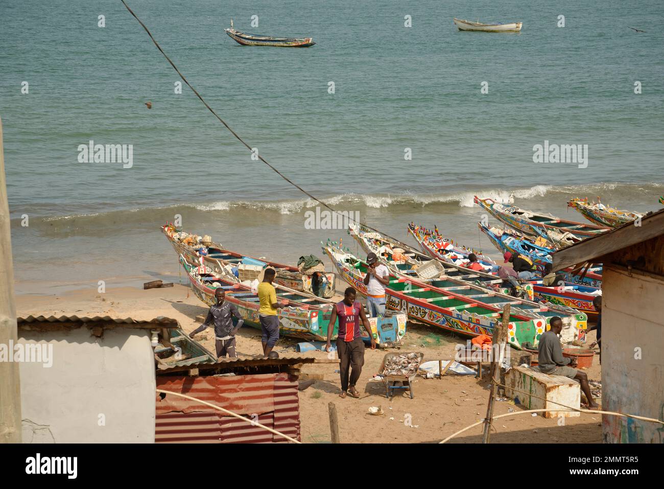 Der Fischereihafen Bakau in Gambia, Westafrika. Fischer und ihre Boote und ein Fischfang in einer Schubkarre. Stockfoto