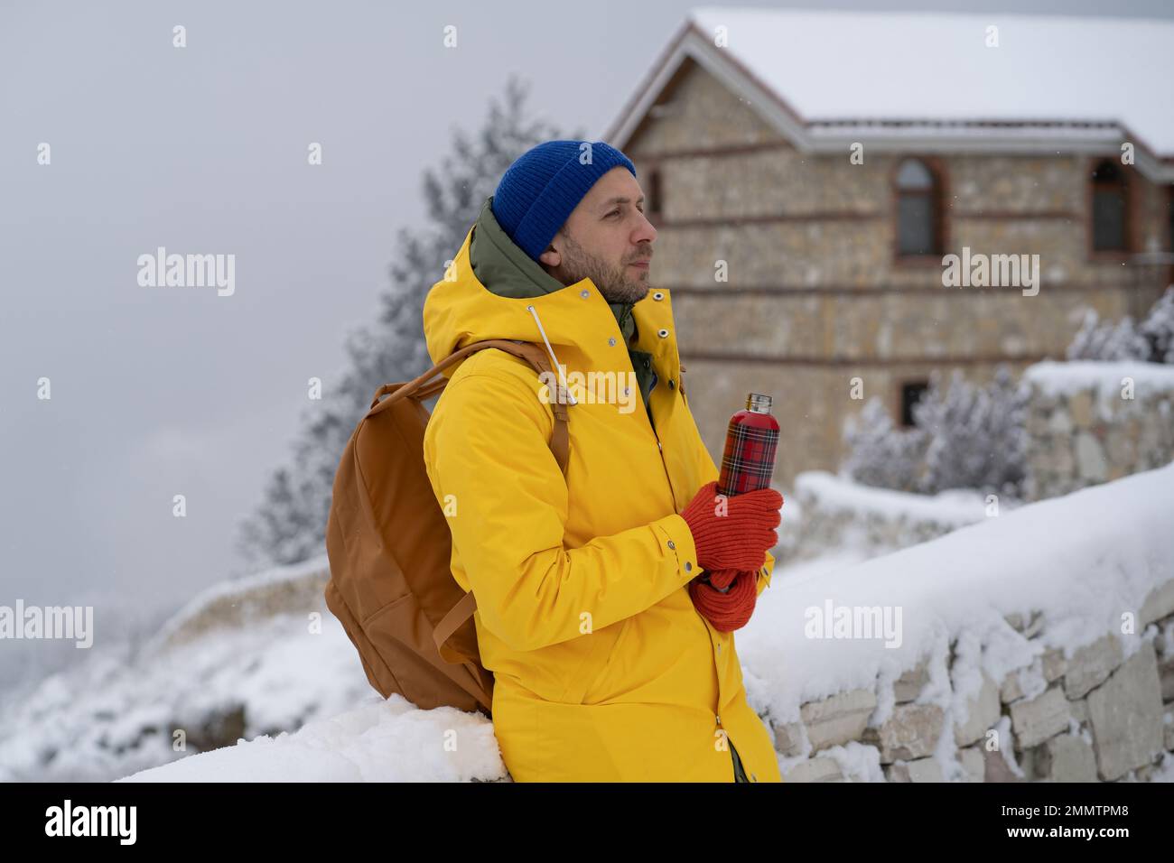 Ein zuversichtlicher Europäer steht draußen mit Thermoskannen, blickt weg, träumt von der Zukunft, denkt an neue Ziele Stockfoto