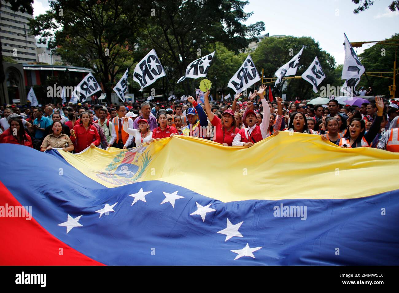 Supporters of Venezuela's President Nicolas Maduro, holding a giant national flag, march to the Miraflores Presidential Palace in Caracas, Venezuela, Monday, Aug. 6, 2018. Venezuelan President Nicolas Maduro dodged an apparent assassination attempt over the weekend when drones armed with explosives detonated while he was delivering a speech to hundreds of soldiers being broadcast live on television, according to officials. (AP Photo/Ariana Cubillos) Stockfoto