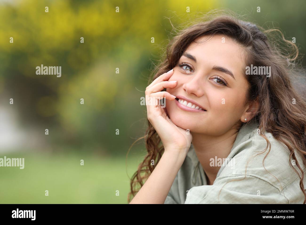 Porträt einer schönen Frau, die dich im Park anlächelt Stockfoto