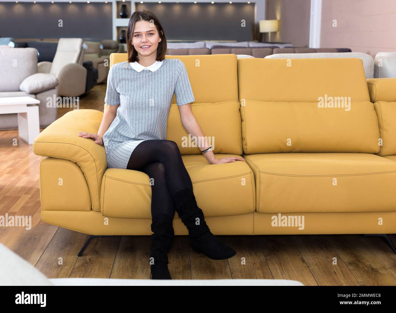 Eine Frau, die auf einem gelben Sofa sitzt Stockfoto