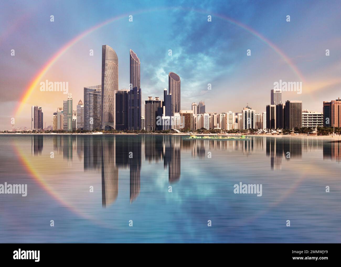 Regenbogen über der Skyline von Abu Dhabi mit Reflexionen im Meer, Vereinigte Arabische Emirate - Panorama Stockfoto
