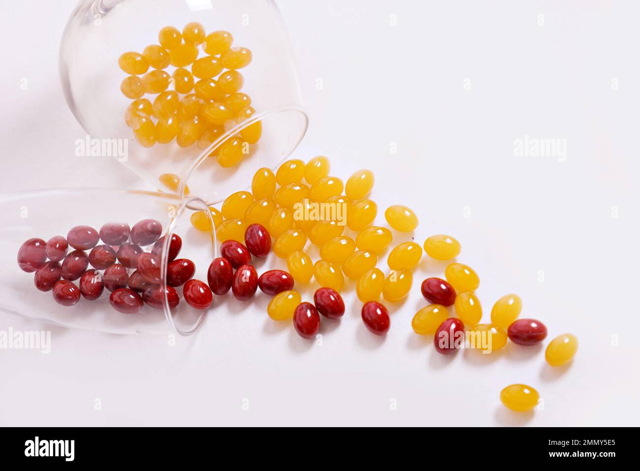 Tabletten, Kapseln zum Sehen. Rote und gelbe Vitamine werden aus dem Glas auf den Tisch gegossen. Dioptrien, Myopie, Weitsicht. Gesunder Körper, Herz und Knochen. Hochwertiges Foto Stockfoto