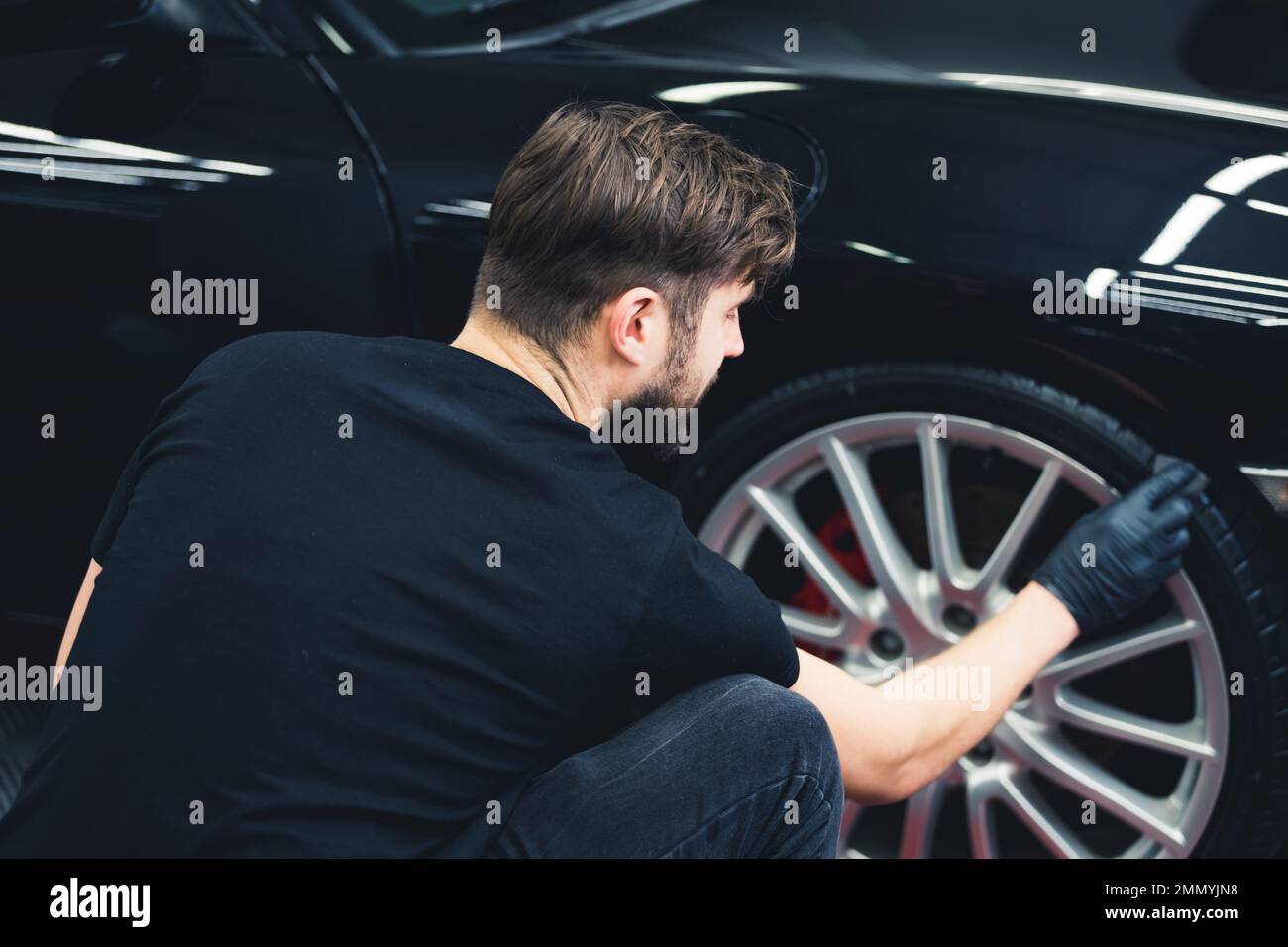Schwärzung des Autoreifens durch Schwamm mit chemischer Schwärzung des Gummis bei der Kfz-Wartung. Rückansicht. Hochwertiges Foto Stockfoto