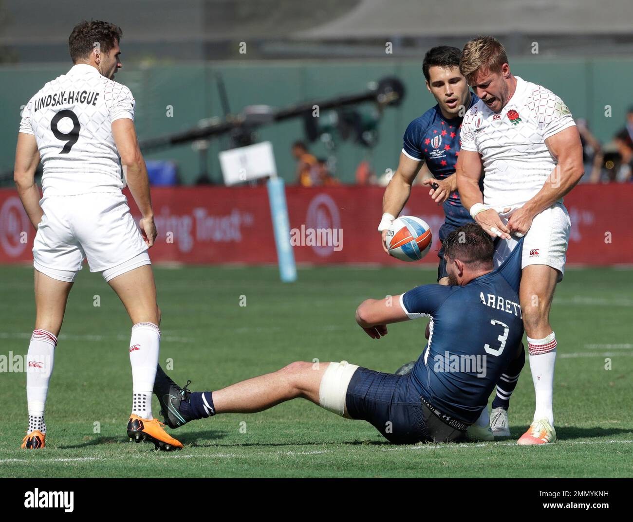 England's Tom Mitchell, right, pulls on the jersey of United States's Dan Barrett, below, as teammate Ollie Lindsay-Hague, left, looks on during the Rugby Sevens World Cup in San Francisco, Saturday, July 21, 2018. (AP Photo/Jeff Chiu) Stockfoto