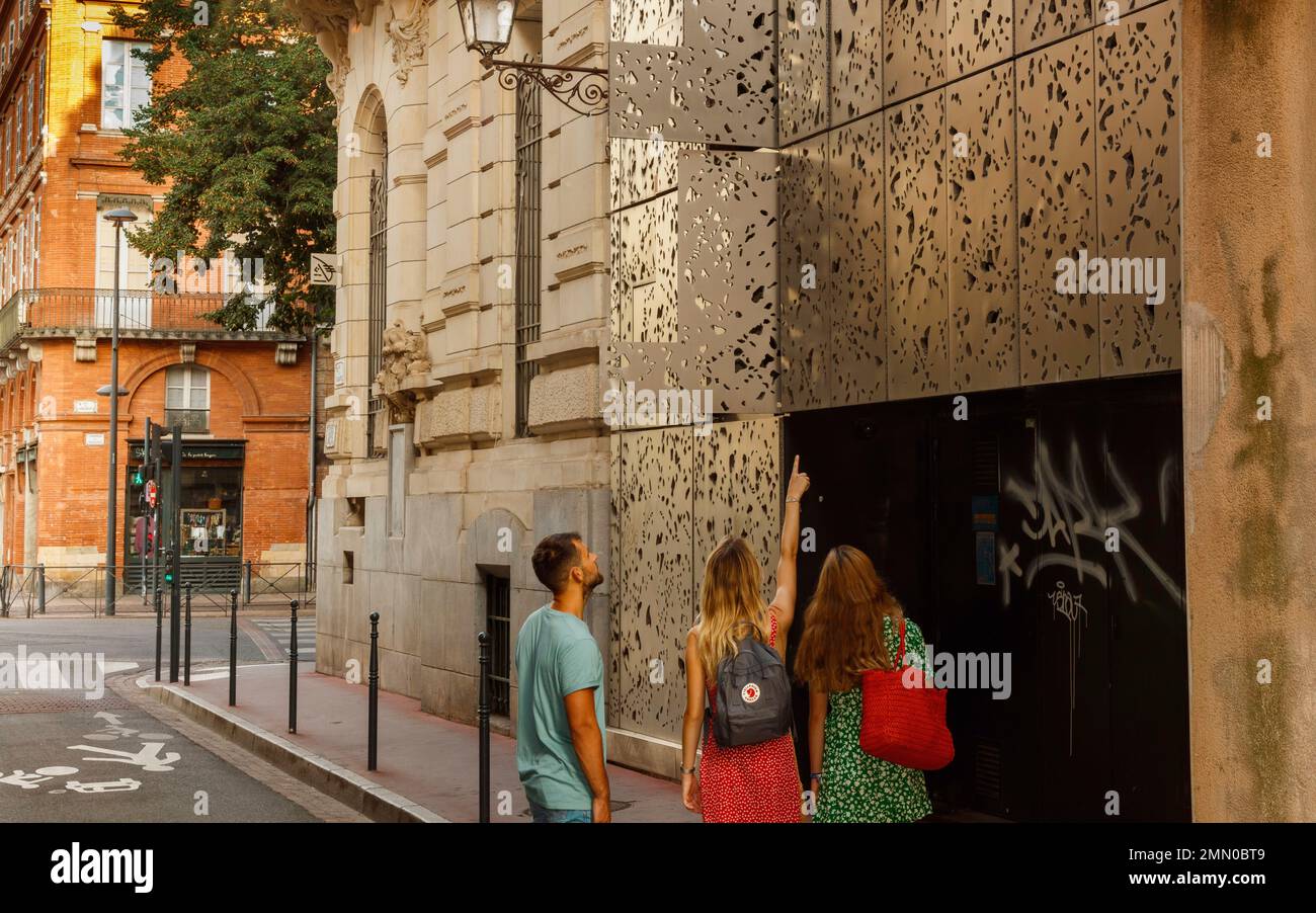 Frankreich, Haute Garonne, Toulouse, Boulevard du Languedoc, Gruppe von 3 Touristenfreunden in einer Straße in der Innenstadt, die im Sommer die Fassade eines modernen Gebäudes beobachtet Stockfoto