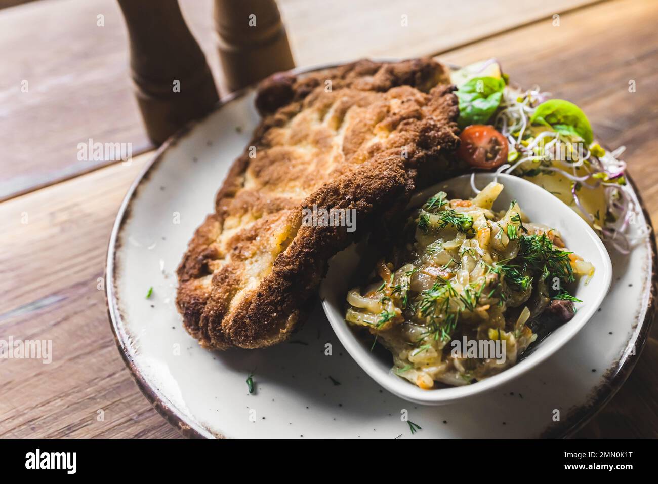 Blick von oben auf paniertes, gebratenes Schweinefleisch mit Schabowy mit gekochten Kartoffeln und Salat auf weißem Teller. Polnische Küche. Horizontale Indoor-Aufnahme. Hochwertiges Foto Stockfoto