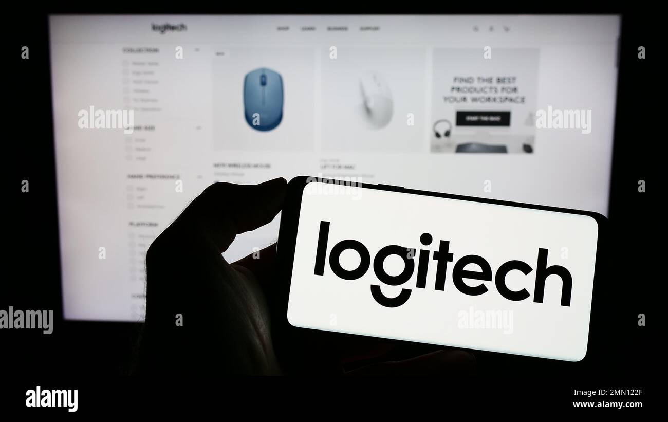 Person, die ein Mobiltelefon mit dem Logo des Schweizer Unternehmens Logitech International S.A. auf dem Bildschirm vor der geschäftlichen Webseite hält. Konzentrieren Sie sich auf das Display des Telefons. Stockfoto