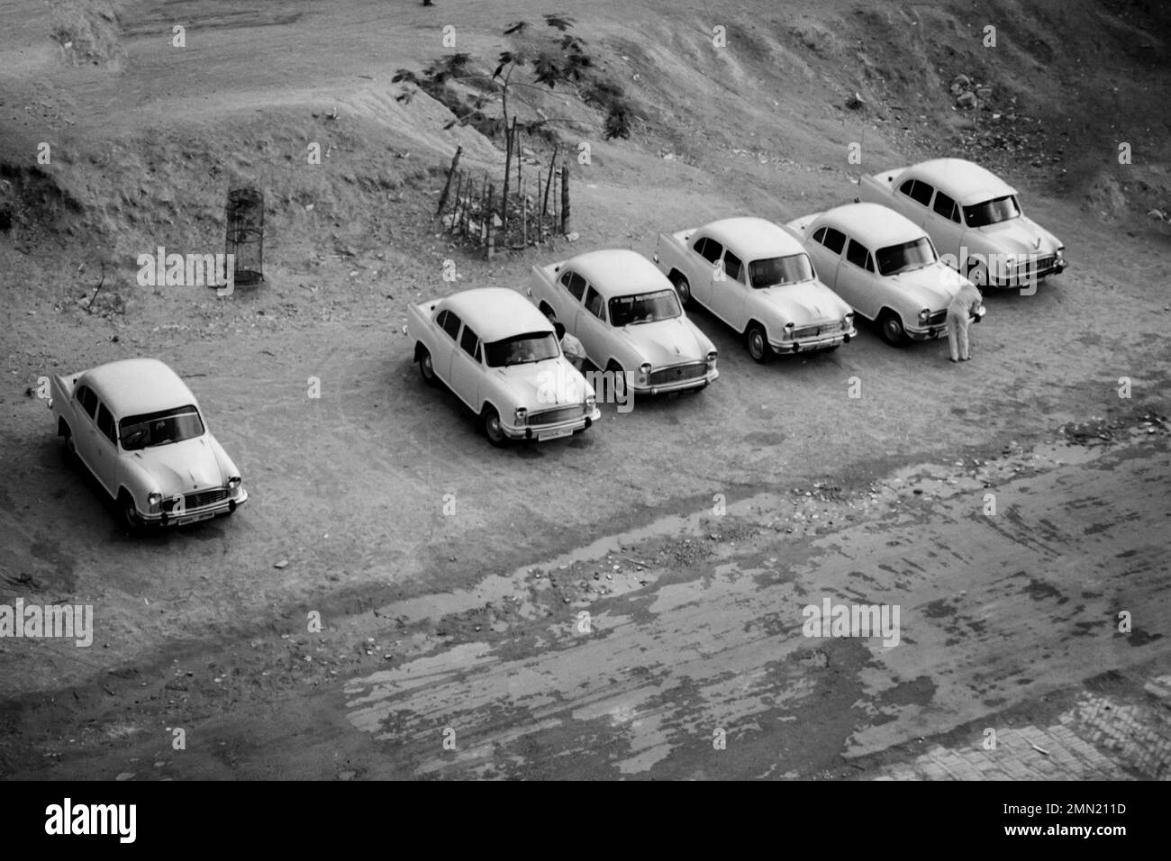 Altes Bild von Oldtimern, die nebeneinander auf einer unbefestigten Straße geparkt sind Stockfoto