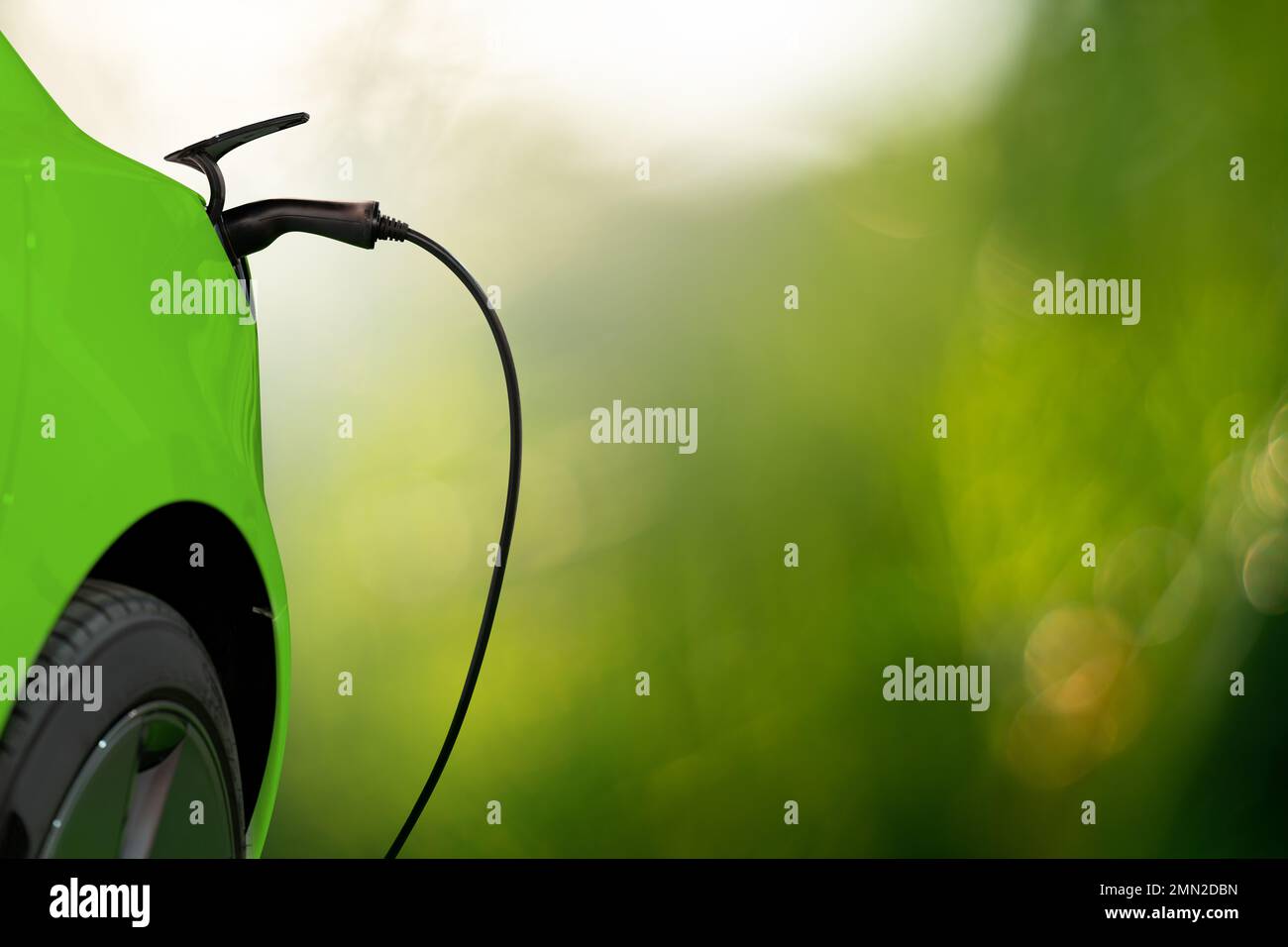 Nahaufnahme des Elektroautos mit angeschlossenem Ladekabel auf grünem Hintergrund Stockfoto