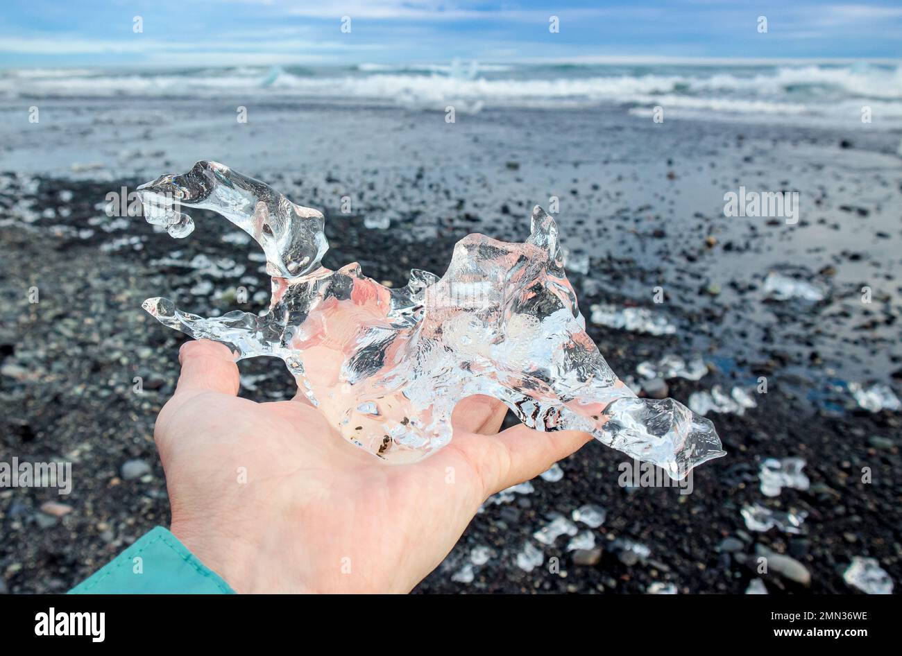 Nahaufnahme einer Touristenfrau, die im Sommer Gletschereis auf dem Island Place namens Diamond Beach hält. Stockfoto
