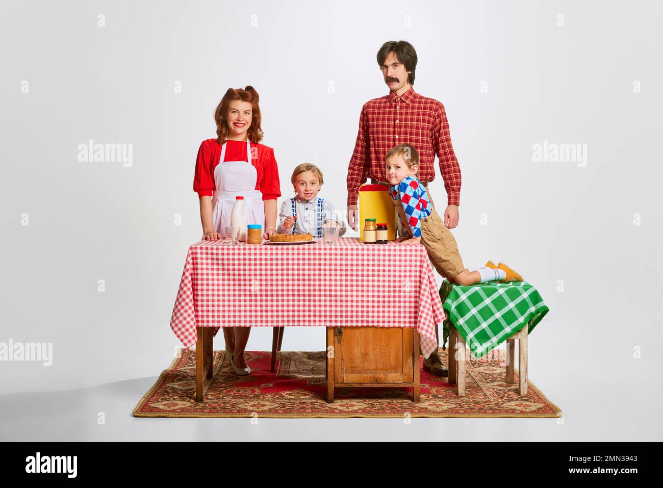 Nette Familie. Mann und Frau stehen am Küchentisch mit zwei kleinen Jungen, Söhnen, bereiten Frühstück vor, kochen Stockfoto