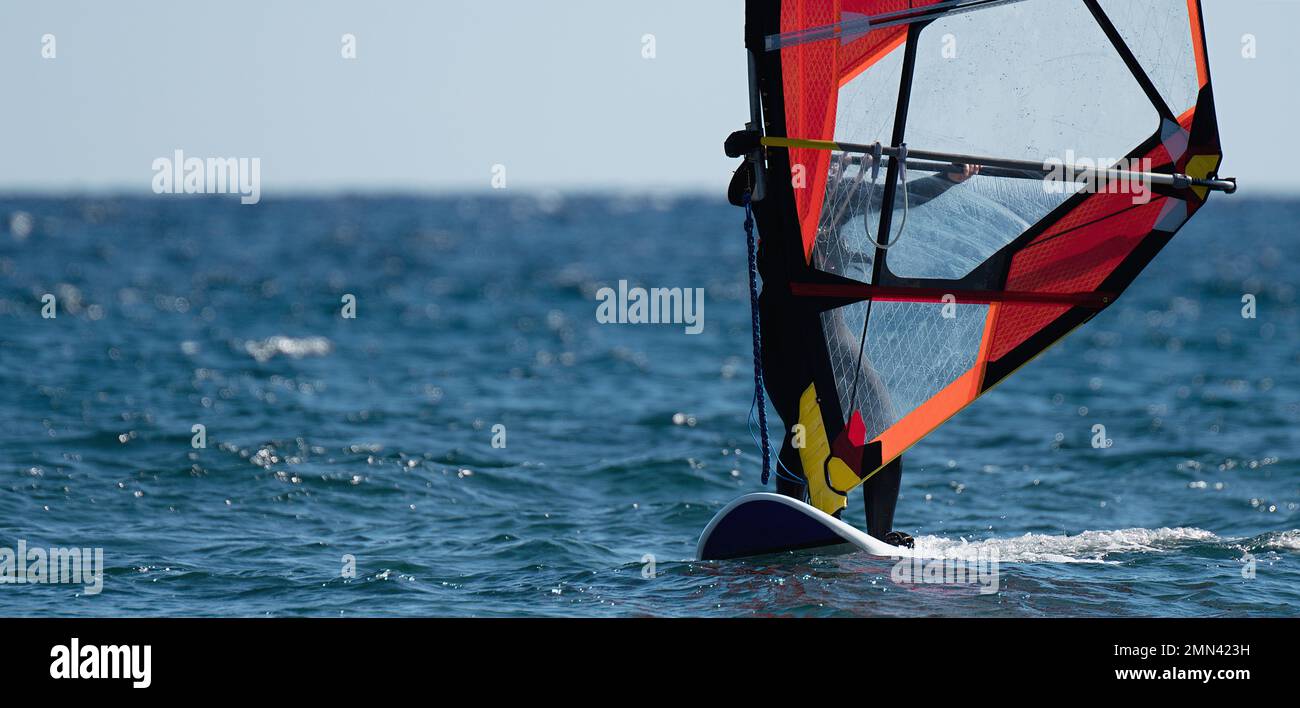 Windsurfer surfen im Wind auf Wellen im Meer, sportliche Freizeitaktivitäten Stockfoto