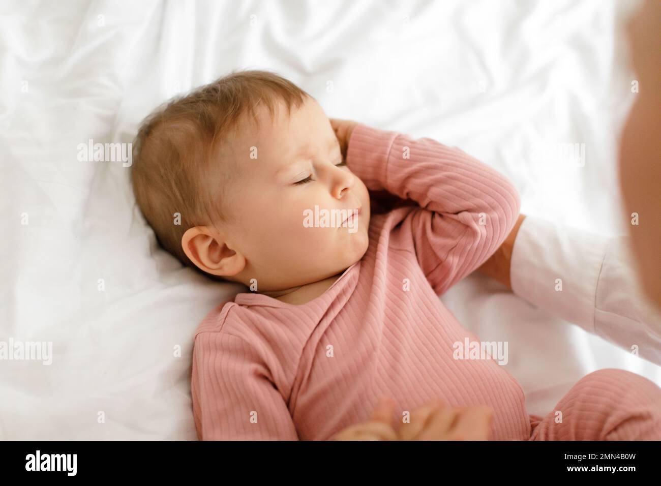 Tagschlafkonzept. Nahaufnahme eines süßen kleinen Mädchens, das im Bett schläft, mit geschlossenen Augen auf weißer Bettwäsche liegt Stockfoto