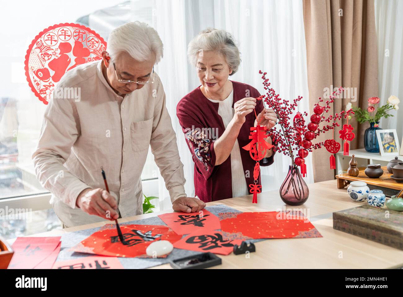 Glücklicher alter Mann und Frau zu Hause, um Kalligraphie zu schreiben Stockfoto
