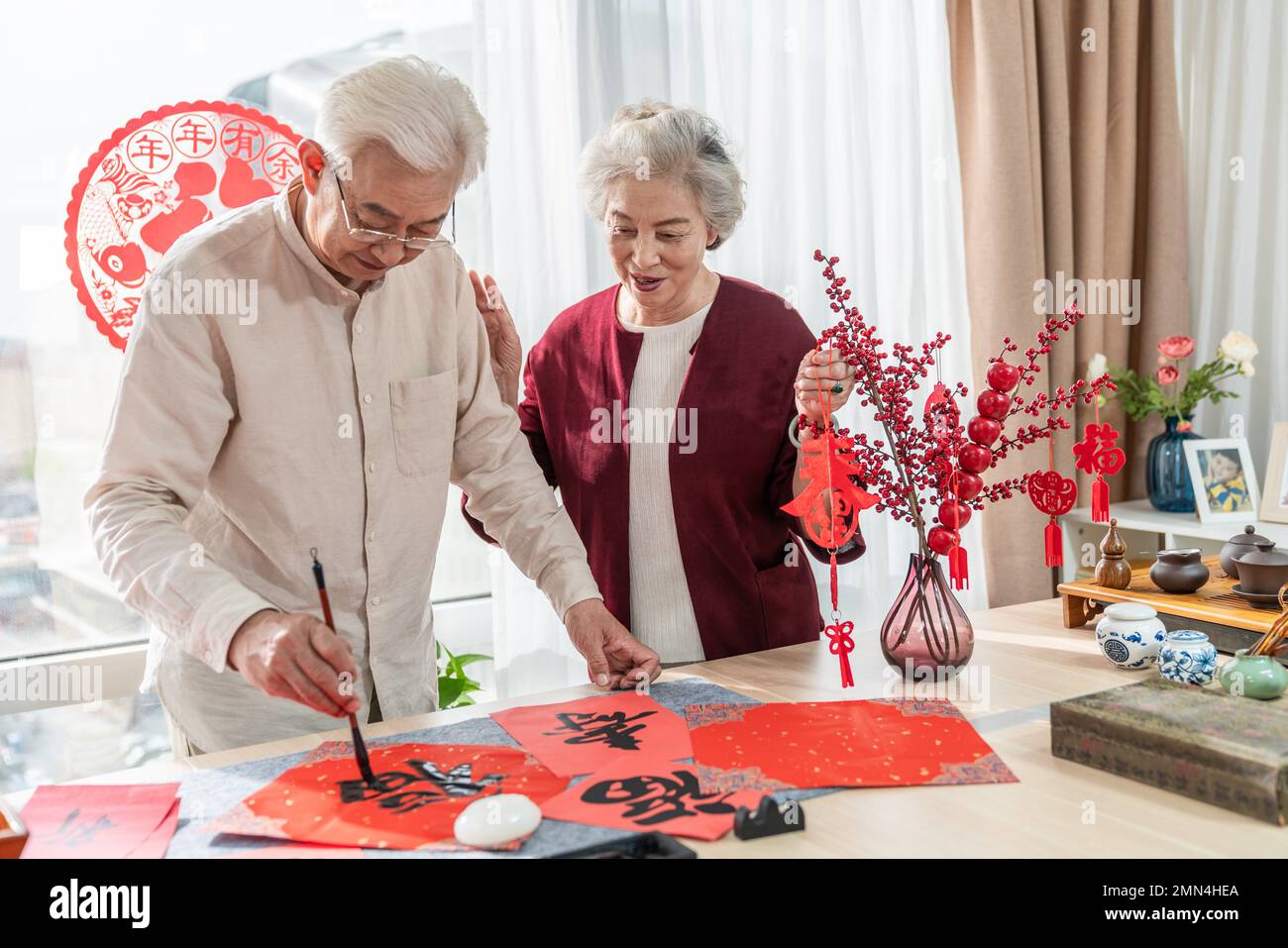 Glücklicher alter Mann und Frau zu Hause, um Kalligraphie zu schreiben Stockfoto