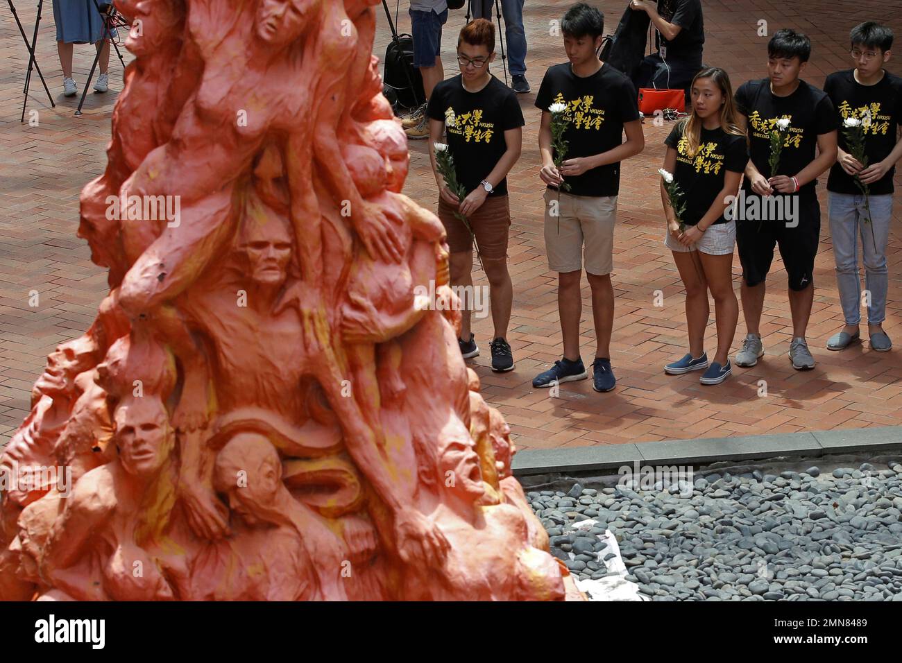 University students place flowers on the "Pillar of Shame" statue, a memorial for those injured and killed in the Tiananmen crackdown, at the University of Hong Kong, Monday, June 4, 2018. Tens of thousands of people are expected to attend an annual candlelight vigil for victims of the Chinese government's military crackdown nearly three decades ago on protesters in Beijing's Tiananmen Square. (AP Photo/Kin Cheung) Stockfoto