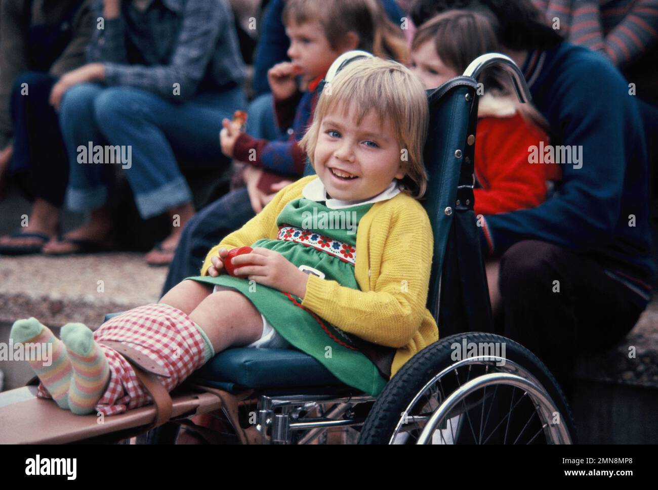 Lifestyle. Kinder. Ein kleines Mädchen im Rollstuhl bei einer Open-Air-Veranstaltung. Stockfoto