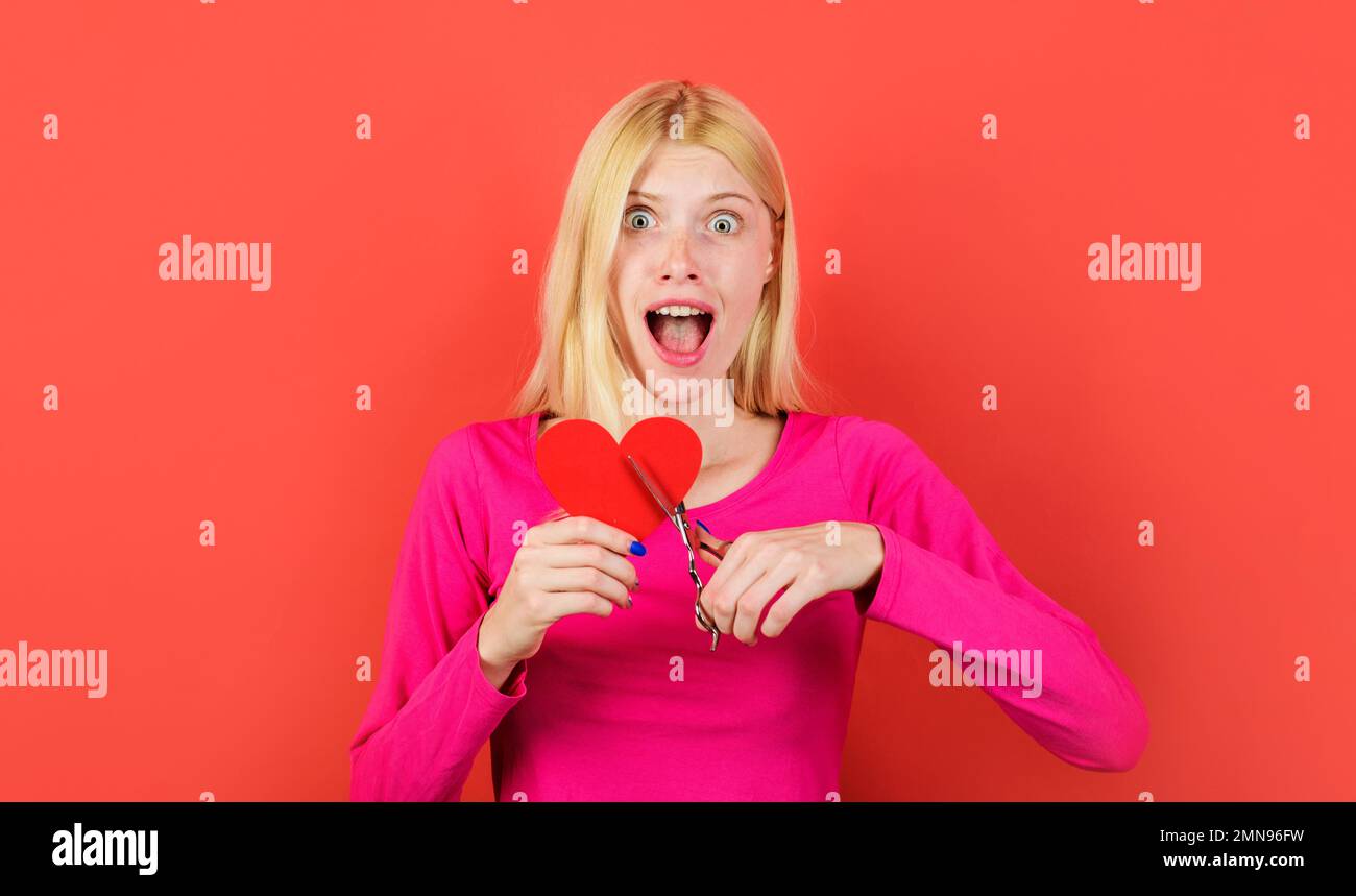 Unerwiderte Liebe. Schöne Frau schneidet rotes Herz mit einer Schere. Beziehungsprobleme. Gebrochenes Herz. Stockfoto