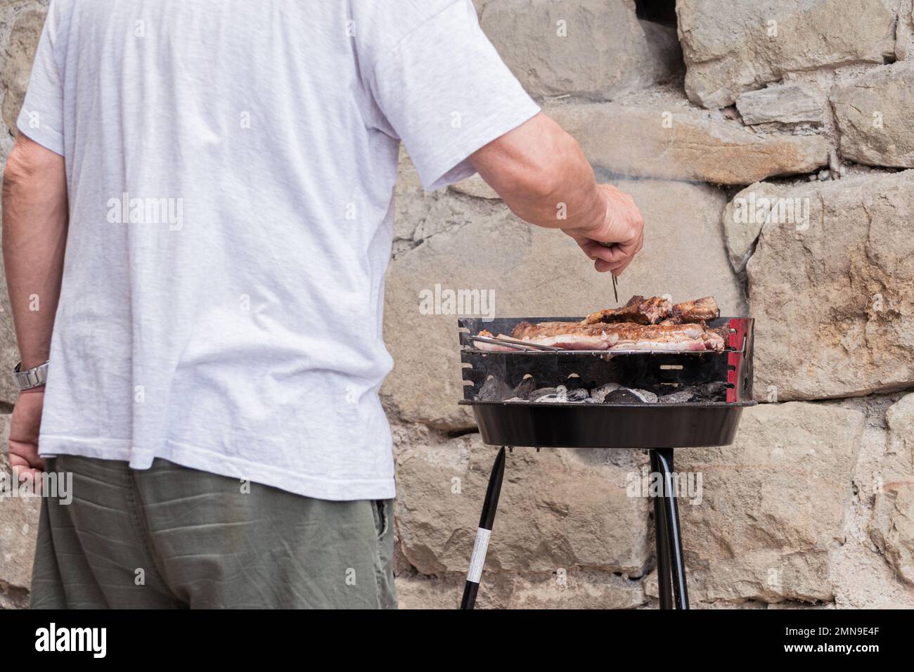 Ein Mann, der Fleisch auf dem Grill kocht Stockfoto