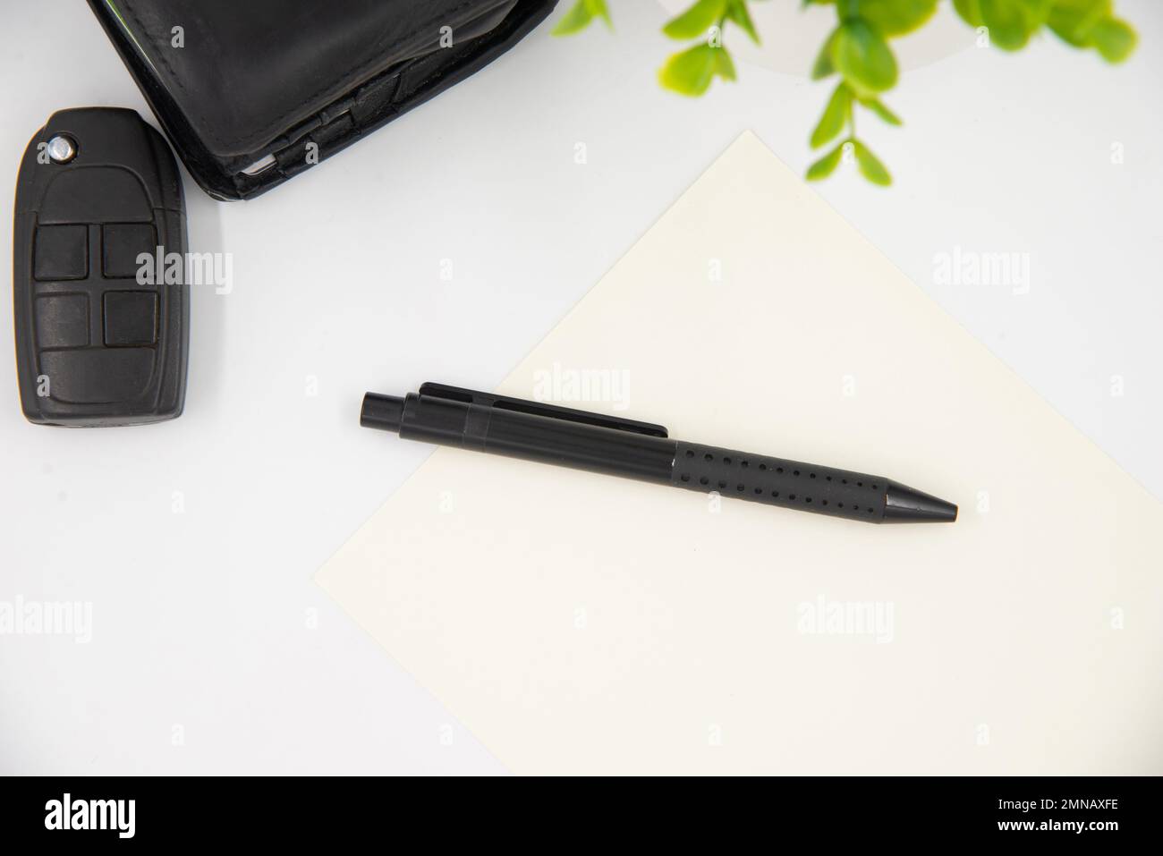 Geschäftsmann-Konzept. Legen Sie den schwarzen Stift auf die weiße Seite neben der schwarzen Brieftasche und den Autoschlüsseln. Stockfoto
