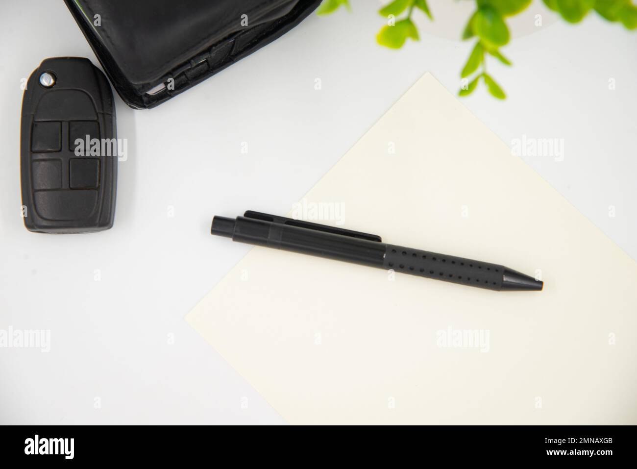 Geschäftsmann-Konzept. Legen Sie den schwarzen Stift auf die weiße Seite neben der schwarzen Brieftasche und den Autoschlüsseln. Stockfoto