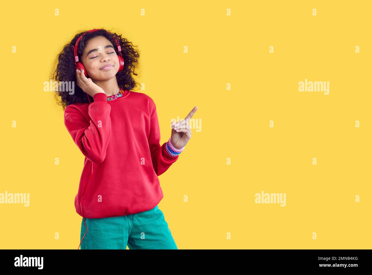 Ein glückliches, birassisches Teenager-Mädchen hört Musik über Kopfhörer Stockfoto
