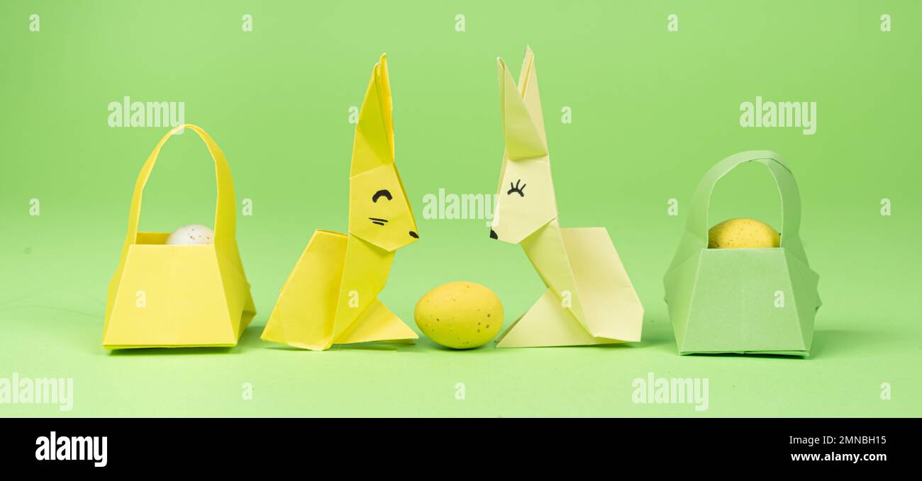 Oster-Origami - zwei Papierhasen und ein Ei mit grünem Hintergrund. Basteln für die Feiertage, machen Sie es selbst. Stockfoto