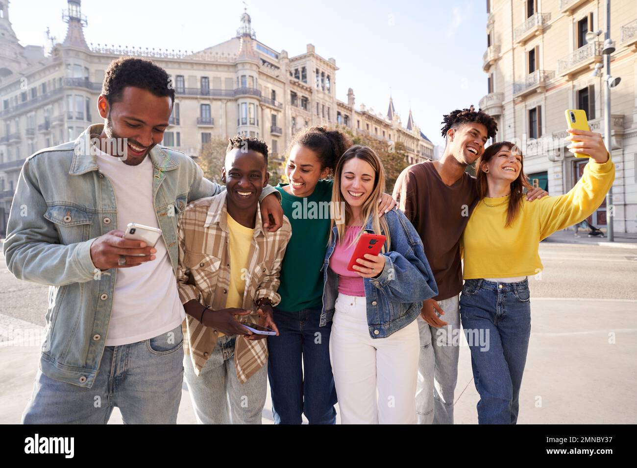 Eine Gruppe multiethnischer Freunde, die draußen auf der Straße rumhängen, spazieren gehen, lachen, telefonieren. Stockfoto