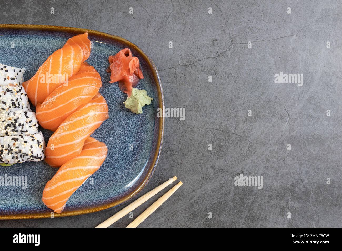 Blick von oben auf klassische Sushi-Brötchen mit Lachs-Nigiris, Wasabi, Ingwer und Essstäbchen mit Kopierbereich Stockfoto