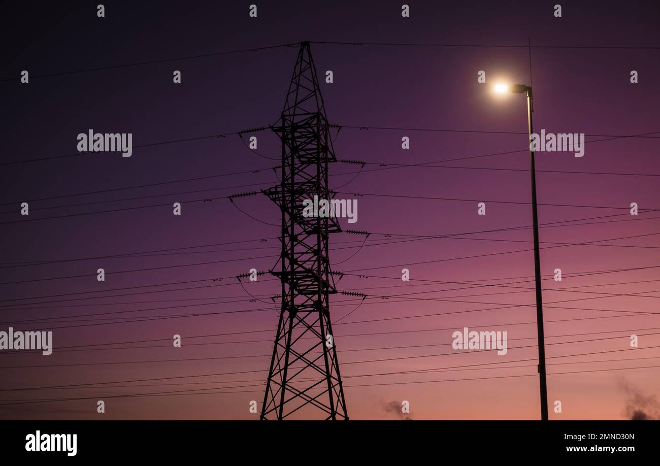 Stromnetz und Sonnenuntergang. Turm und Leitungen. Hohe Strom- und Energiemarktpreise. Hohe Strom- und Energiemarktpreise. Stockfoto