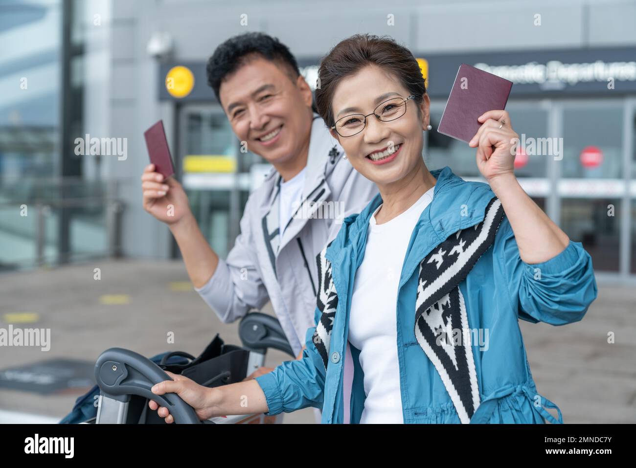 Glückliche ältere Paare, die am Flughafen ein Auto schieben Stockfoto