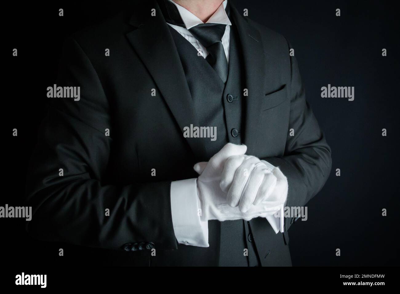 Porträt von Butler in dunklem Anzug und weißen Handschuhen, die gerne zu Diensten sein möchten. Konzept der Dienstleistungsbranche und des professionellen Gastgewerbes. Stockfoto