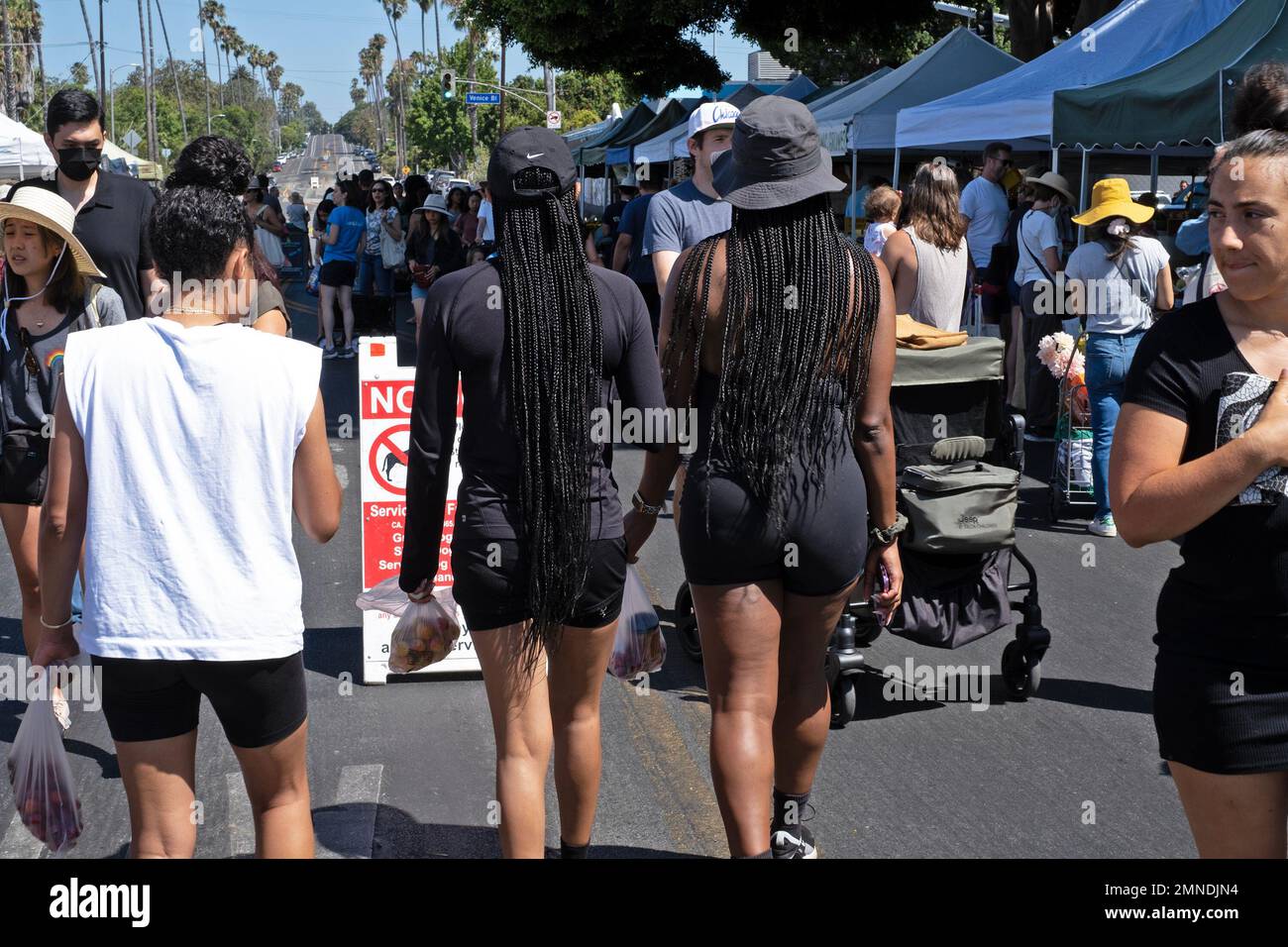 Zwei Frauen tragen lange Zöpfe auf einem Farmer's Market in Los Angeles, Kalifornien, USA. Stockfoto