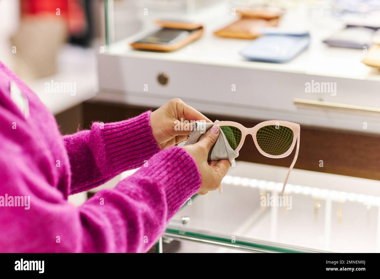 Nahaufnahme eines Verkäufers, der eine modische Sonnenbrille in einer luxuriösen Boutique abwischt, Kopierraum Stockfoto