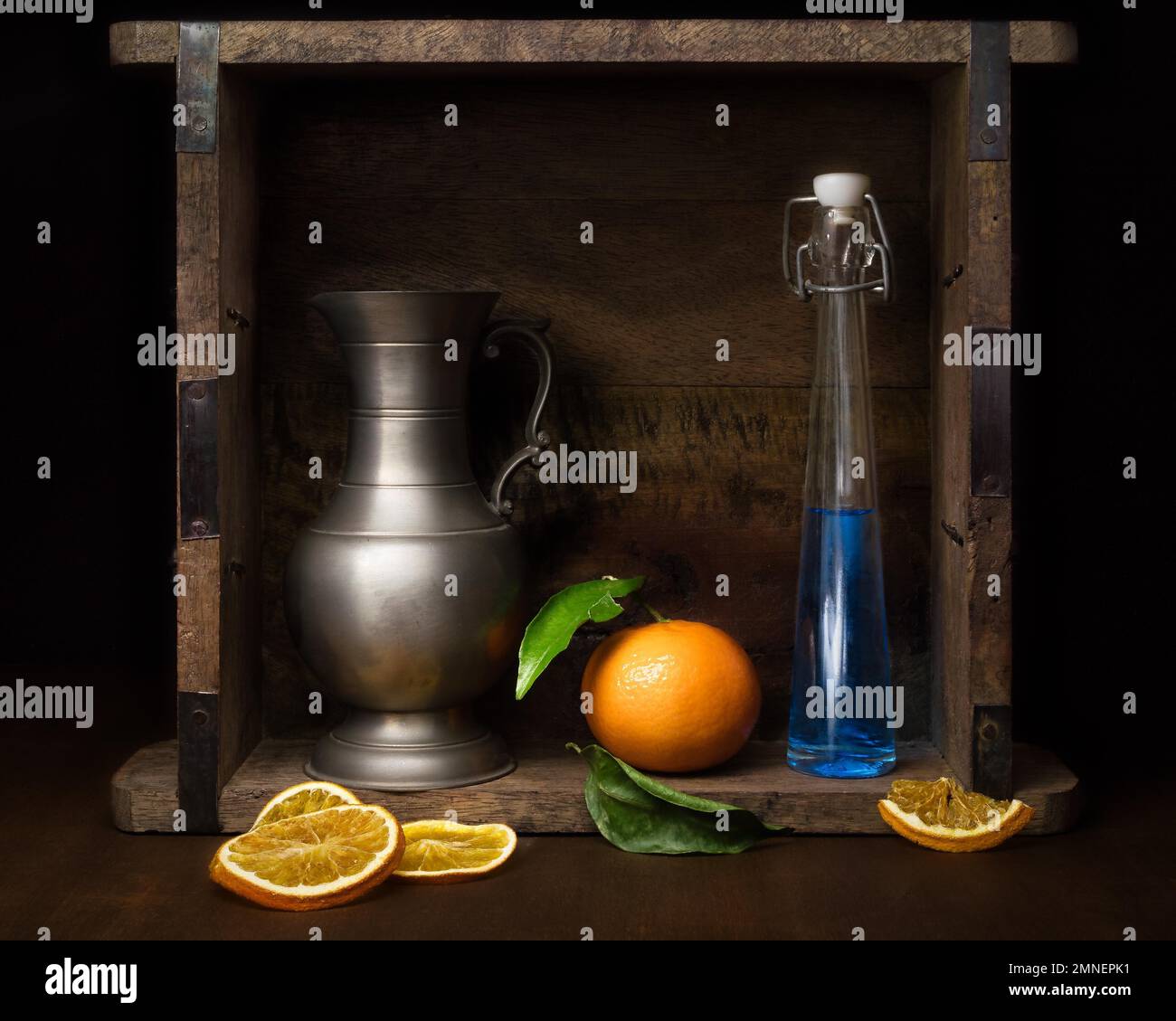 Stillleben mit Glasflasche, Mandarine und Zinnkrug, Studioaufnahme, dunkler Hintergrund Stockfoto