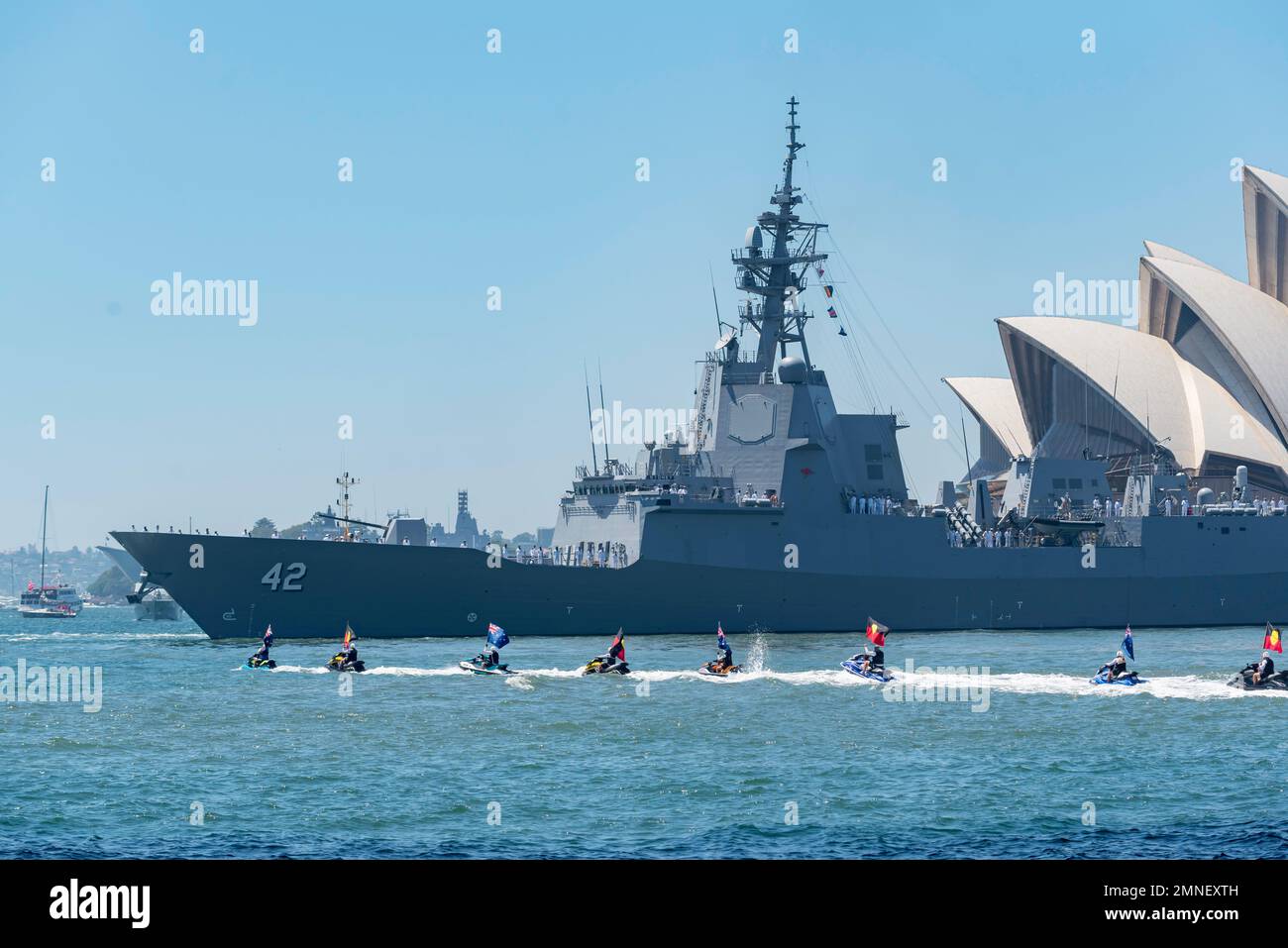 Jetskis mit australischen und indigenen Flaggen und HMAS Sydney(V) im Hafen von Sydney während der Feierlichkeiten zum Australientag am 26. Januar 2023 Stockfoto