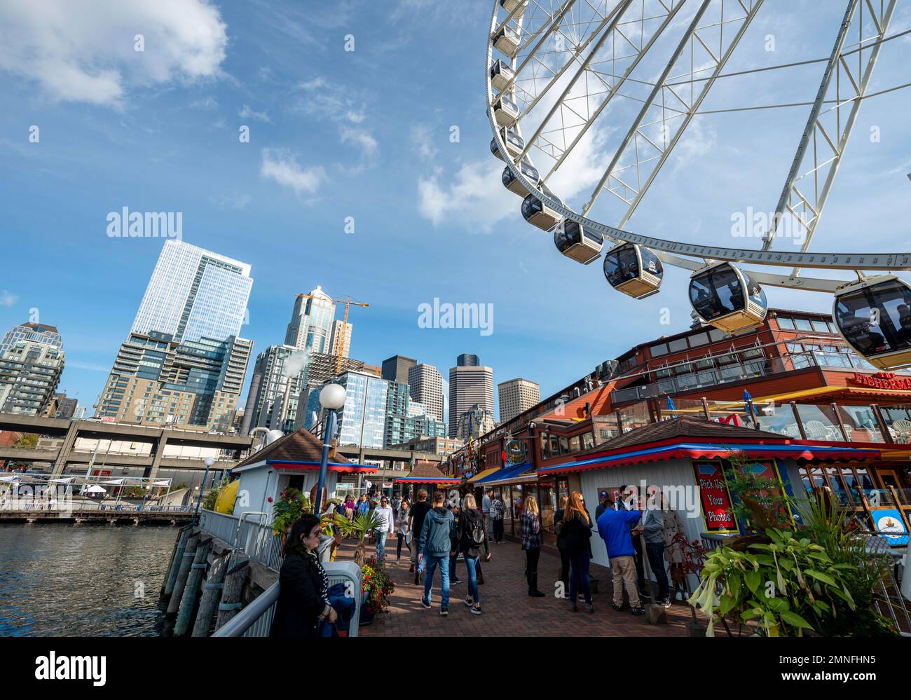 Uferpromenade mit dem Seattle Great Wheel, Wolkenkratzer dahinter, Pier 57, Seattle, Washington, USA Stockfoto