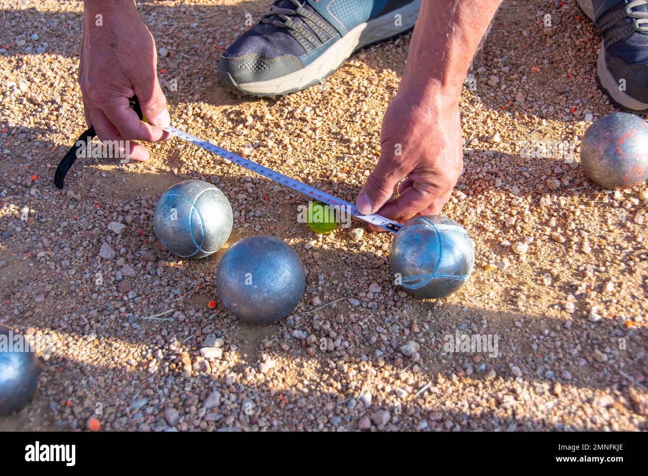 Messen mit einem Maßband im Spiel Petanque (Boule) Stockfoto