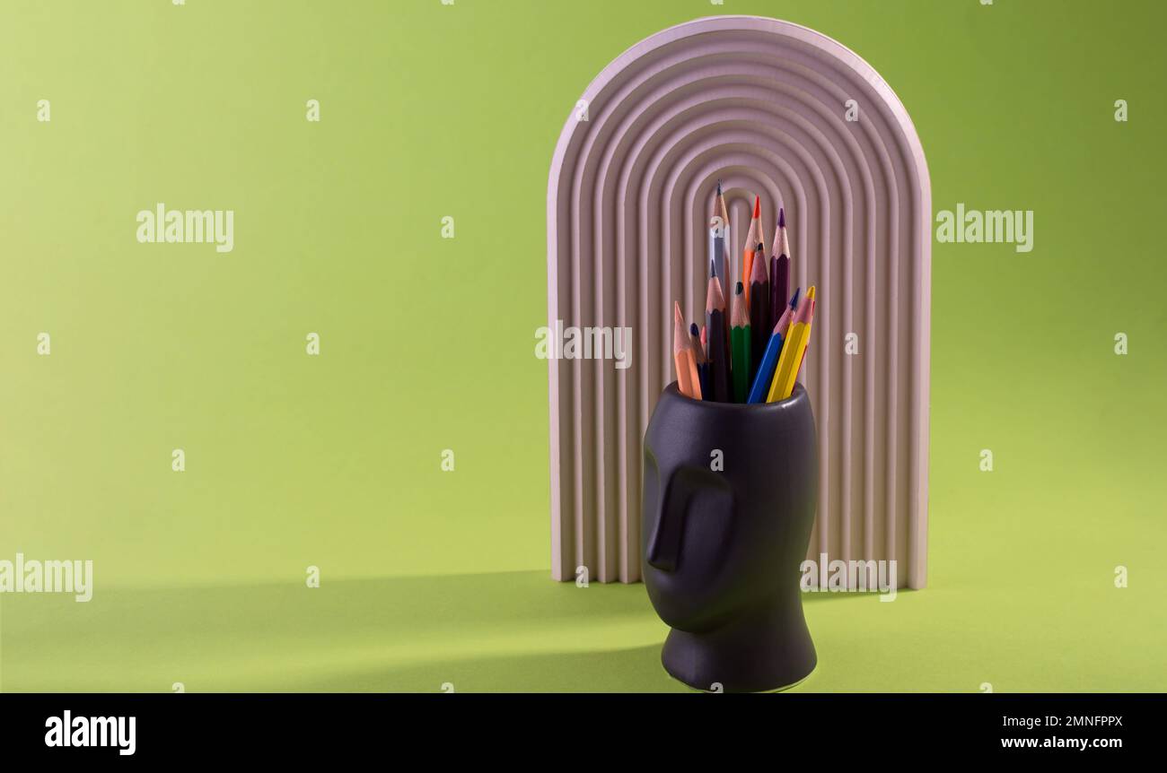 Die bunten Bleistifte werden in Vasenform gegen ein Grün gelegt. Stockfoto
