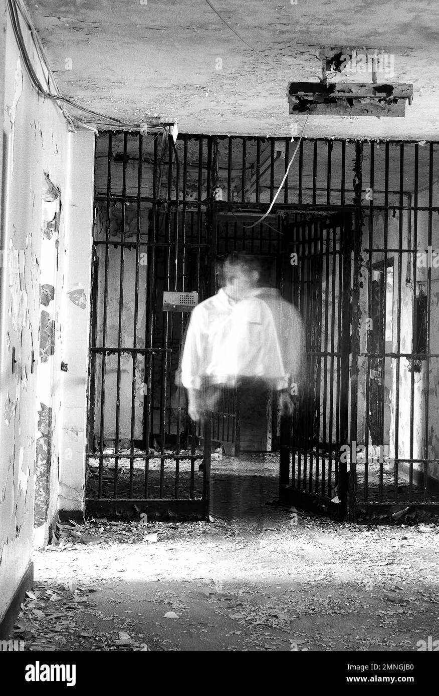Geisterartiger Mann, der in der Nähe der Zelle des verlassenen Gebäudes steht Stockfoto