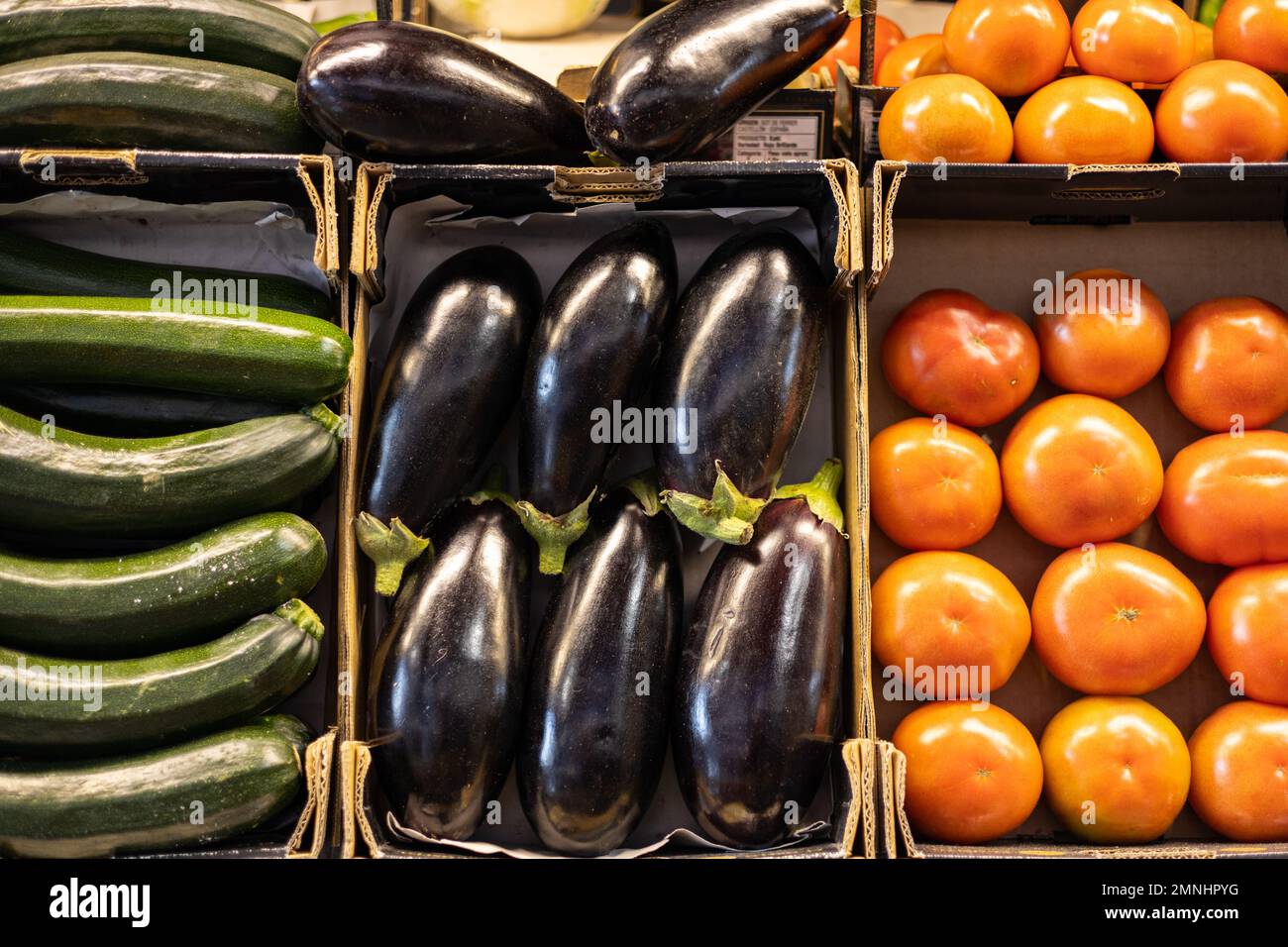 Farbenfrohes Bio-Sommergemüse, Tomaten, Zucchini und Auberginen in Schachteln, die auf dem lokalen Obst- und Gemüsemarkt verkauft werden Stockfoto