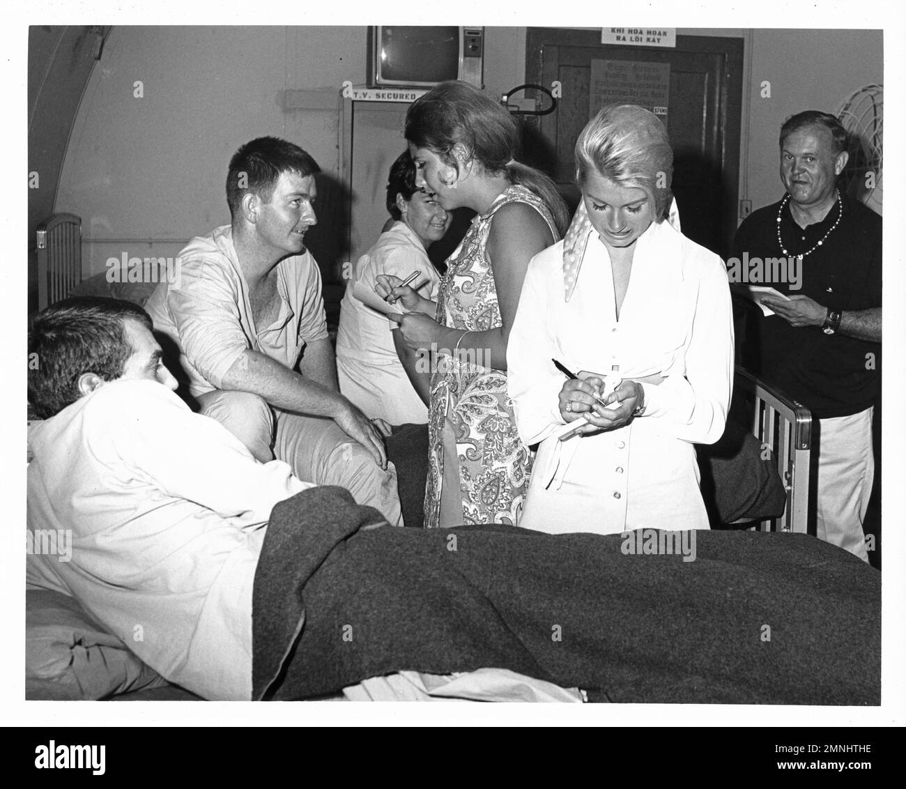 [Naval Support Activity Hospital Danang, Vietnam]. VON USO gesponserte Handshake-Tour. (Donna DeVorona, Marsha Bennett und Johnny Grant signieren Autogramme für verwundete Marines). [Vietnamkrieg]. Ca. 29. Juni 1969 Stockfoto