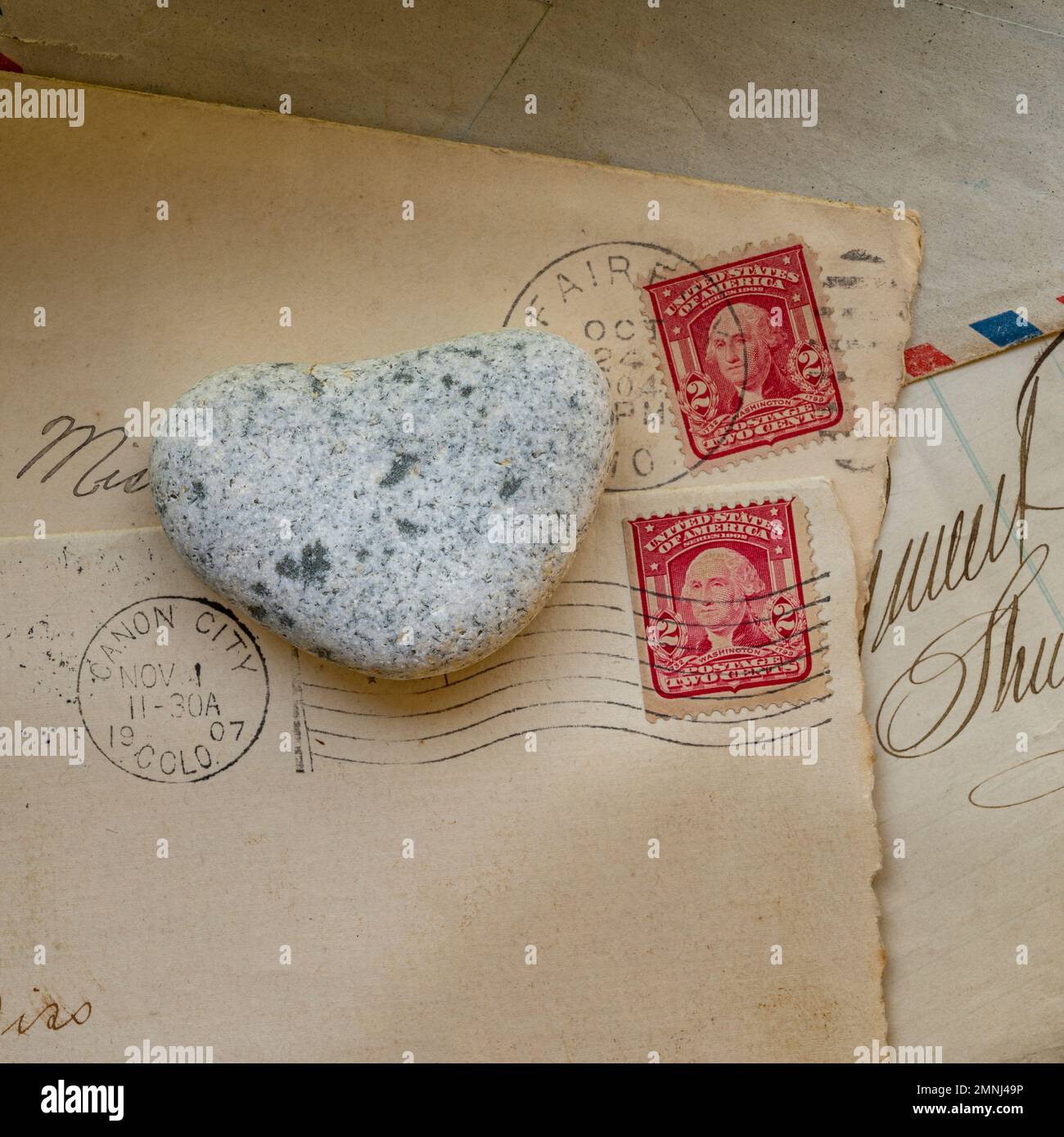 Alte Briefumschläge mit Briefmarken und herzförmigem Stein Stockfoto