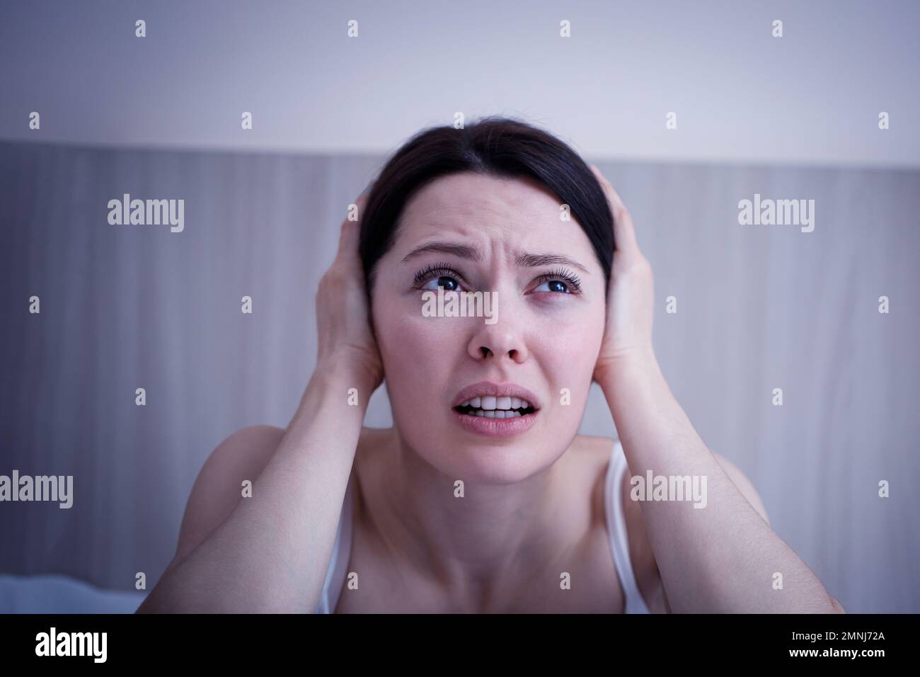 Panikattacke bei Frauen. Die deprimierte junge Dame, die auf der Couch sitzt und den Kopf mit Händen umarmt. Psychologische Problembegriffe. Stockfoto