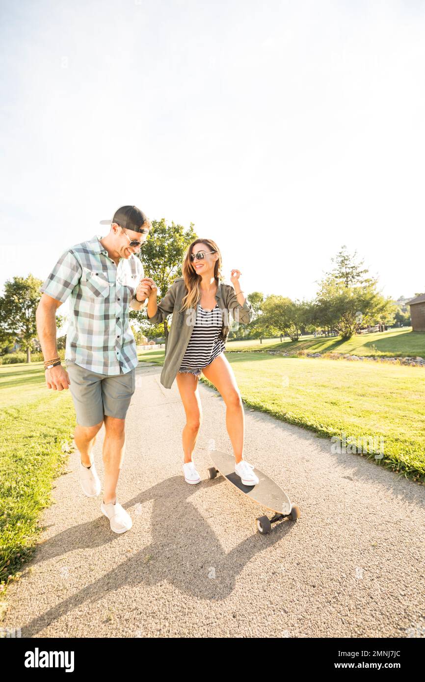 Lächelndes Paar mit Skateboard im Park Stockfoto