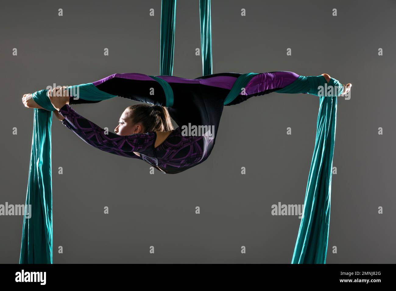 Junger akrobat, der Spaltungen auf Luftseide macht Stockfoto