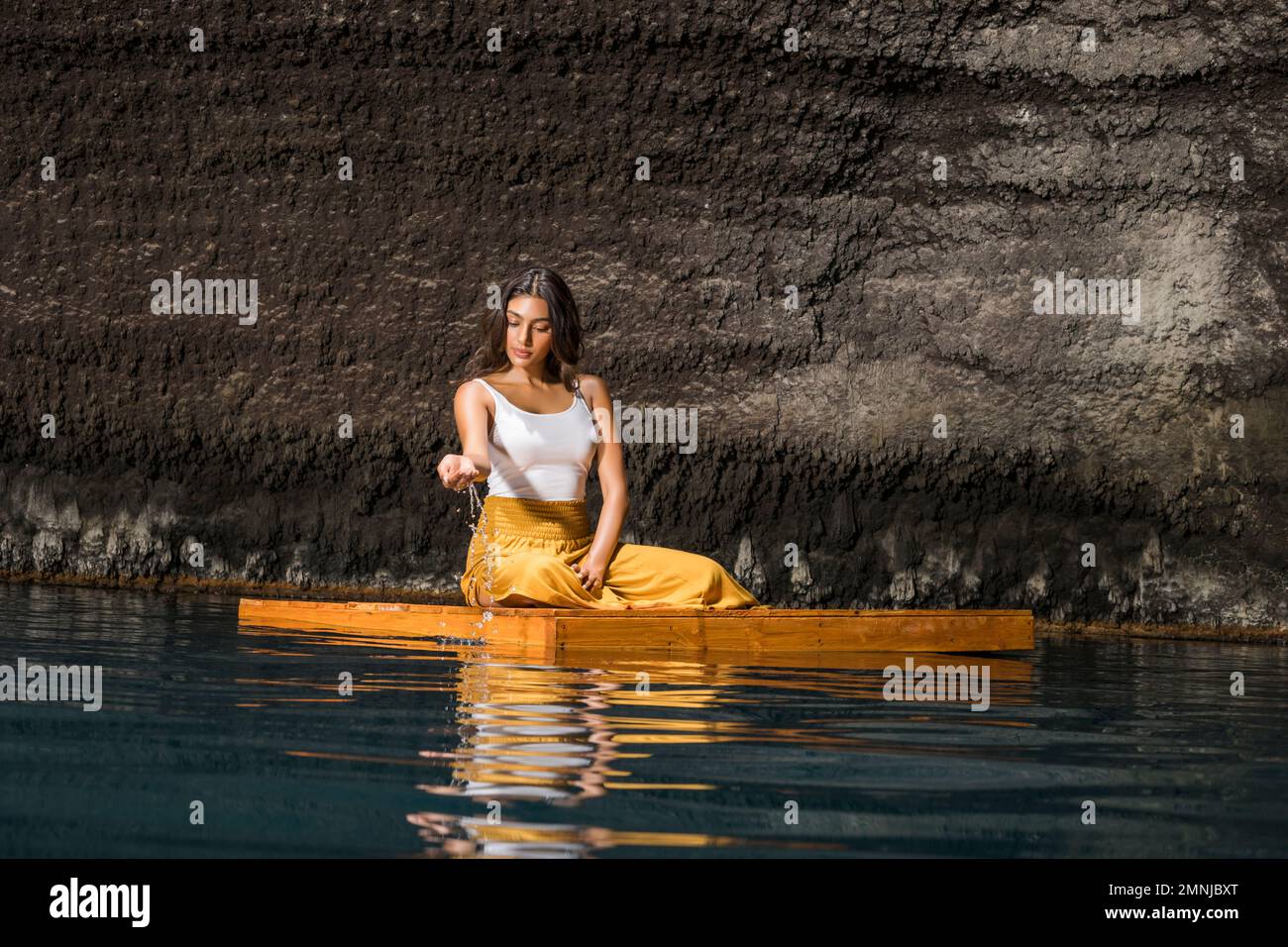 Eine Frau, die auf einem Holzfloß in einer Cenote sitzt Stockfoto