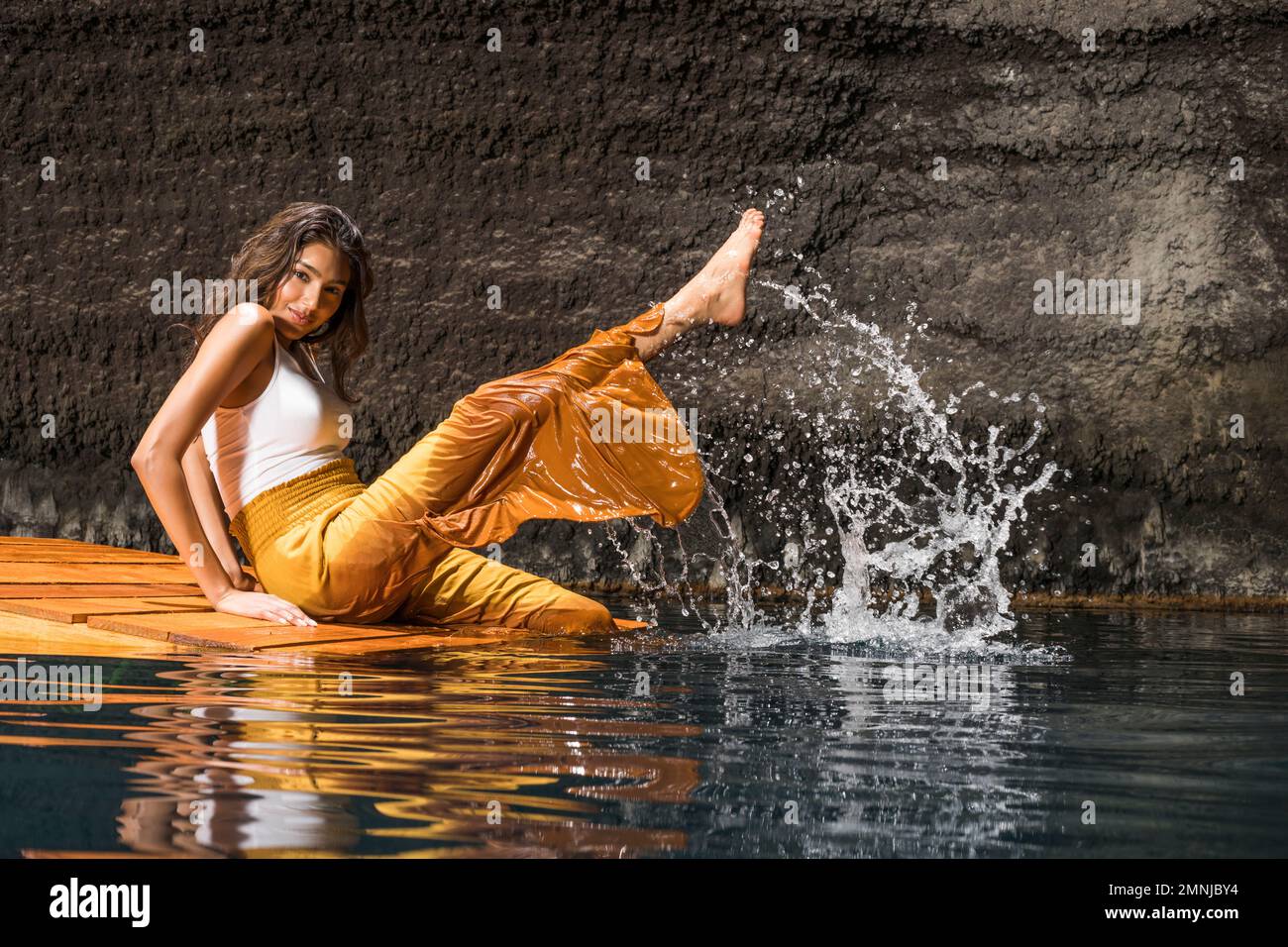 Schöne Frau, die Wasser auf einem Holzfloß in Cenote spritzt Stockfoto